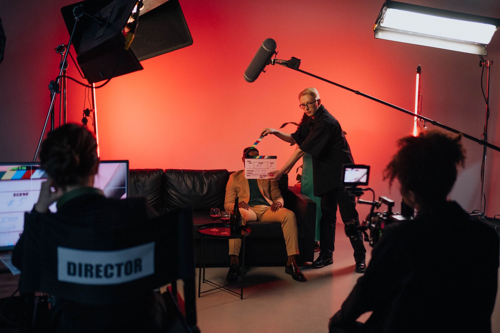 A film set in action — director's chair, boom microphone and an actor on a couch under studio lights